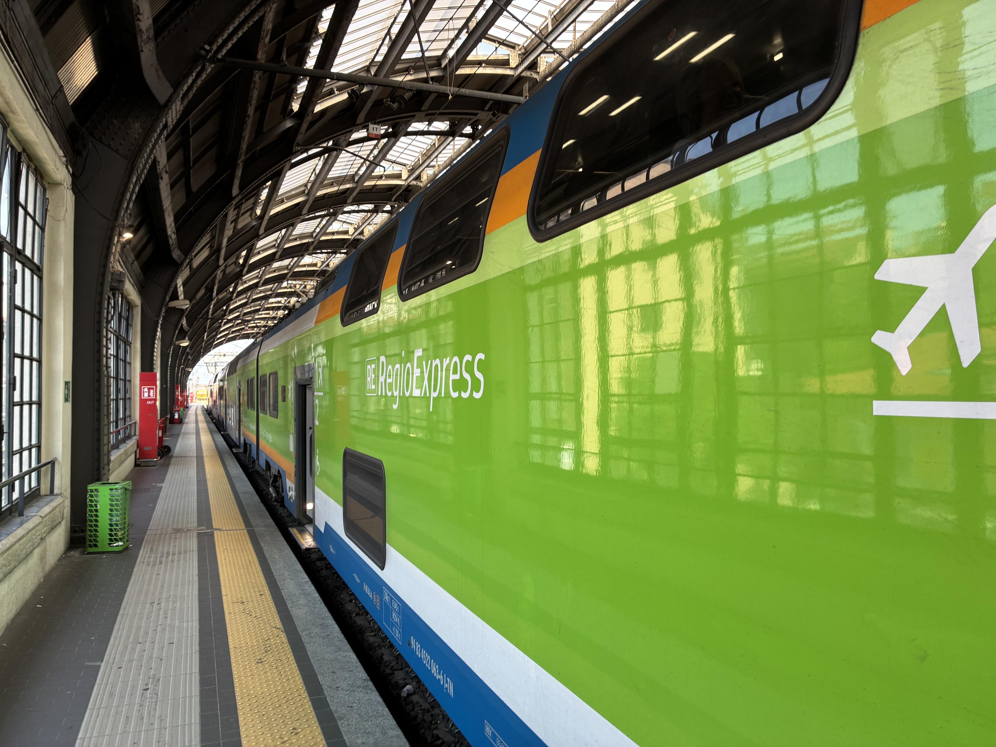 side of the Trenord RegioExpress train in a very green livery, with a white plane symbol indicating it’s running on the Malpensa Express line