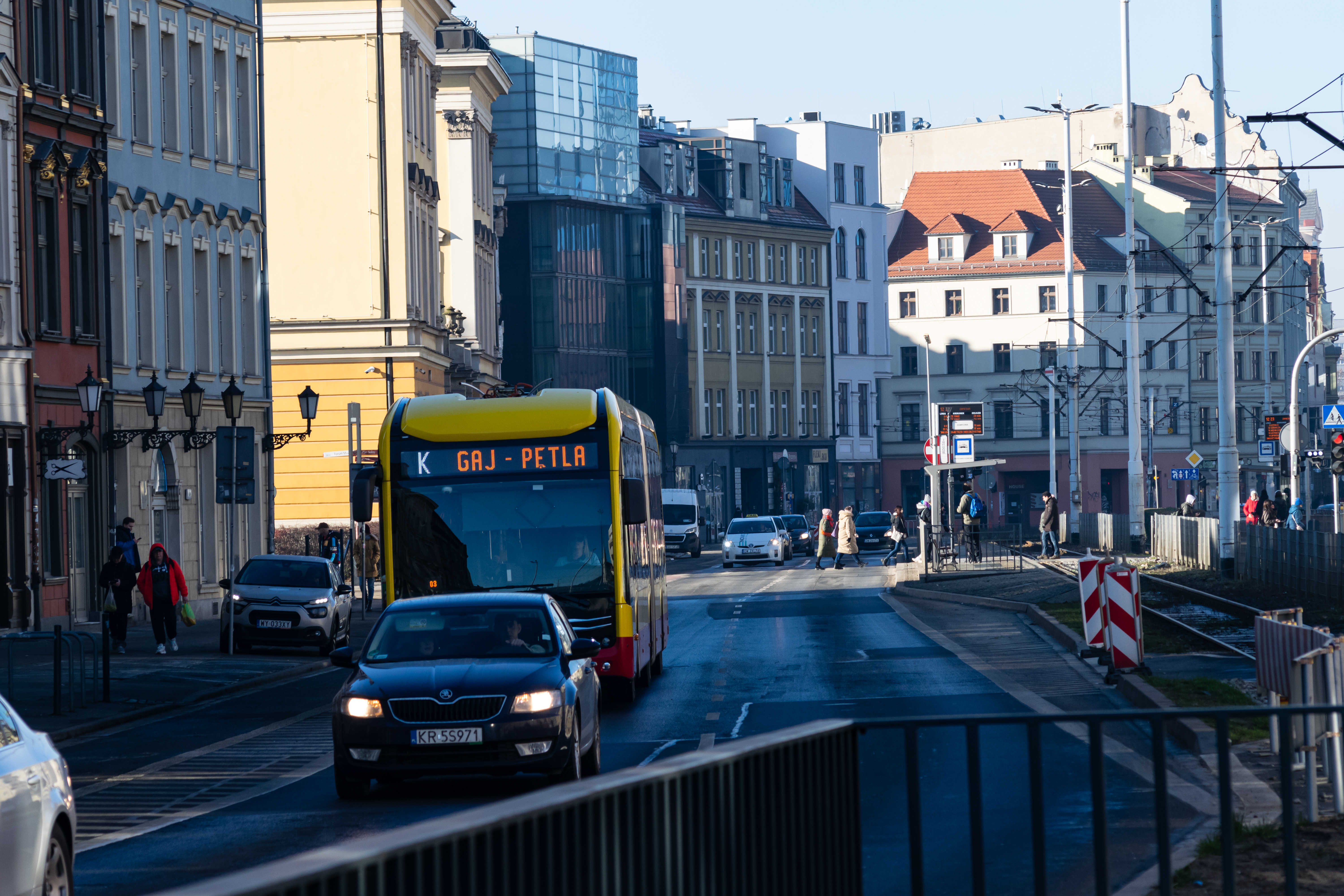 yellow-red electric bus behind a car