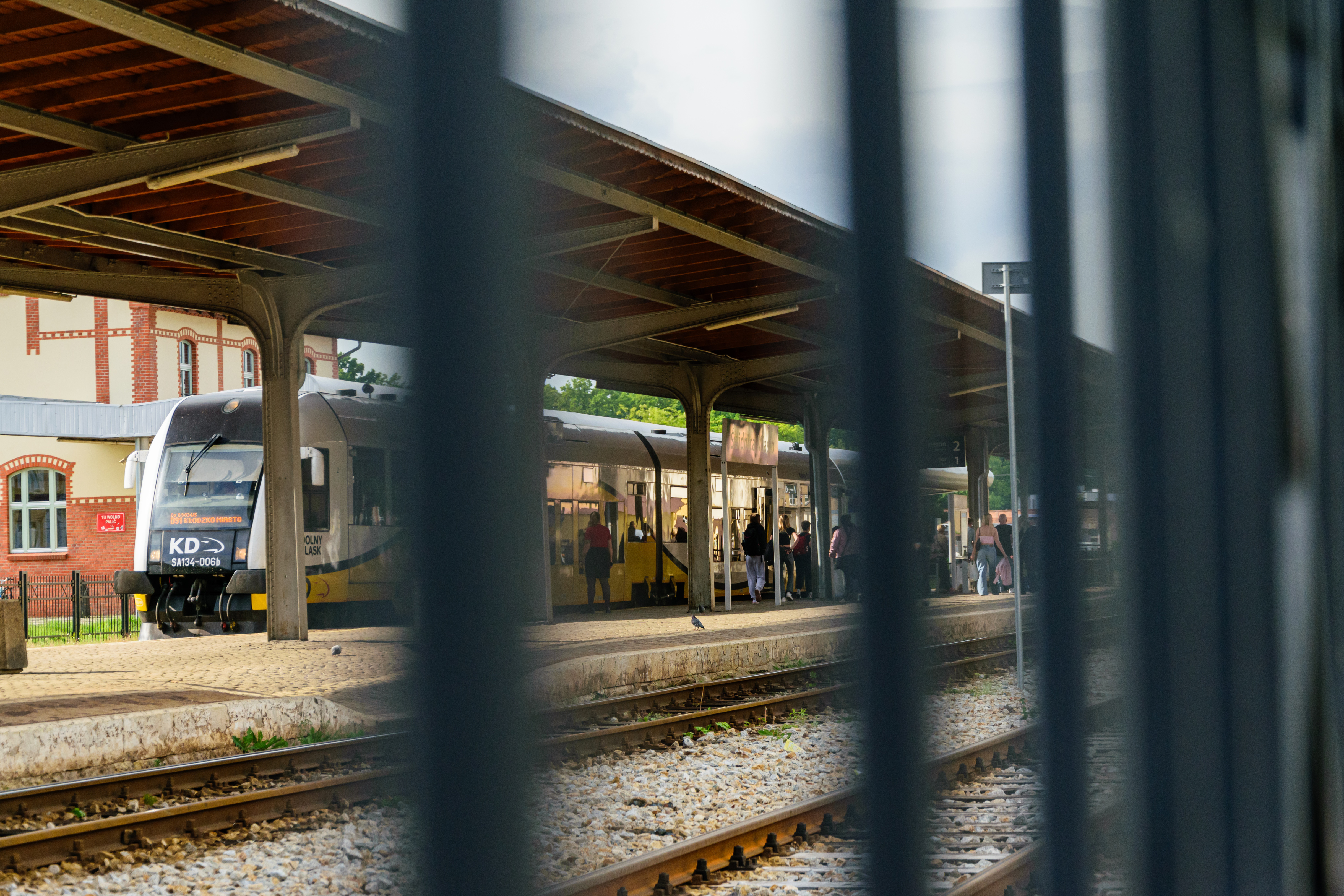 White-yellow train viewed from behind a fence