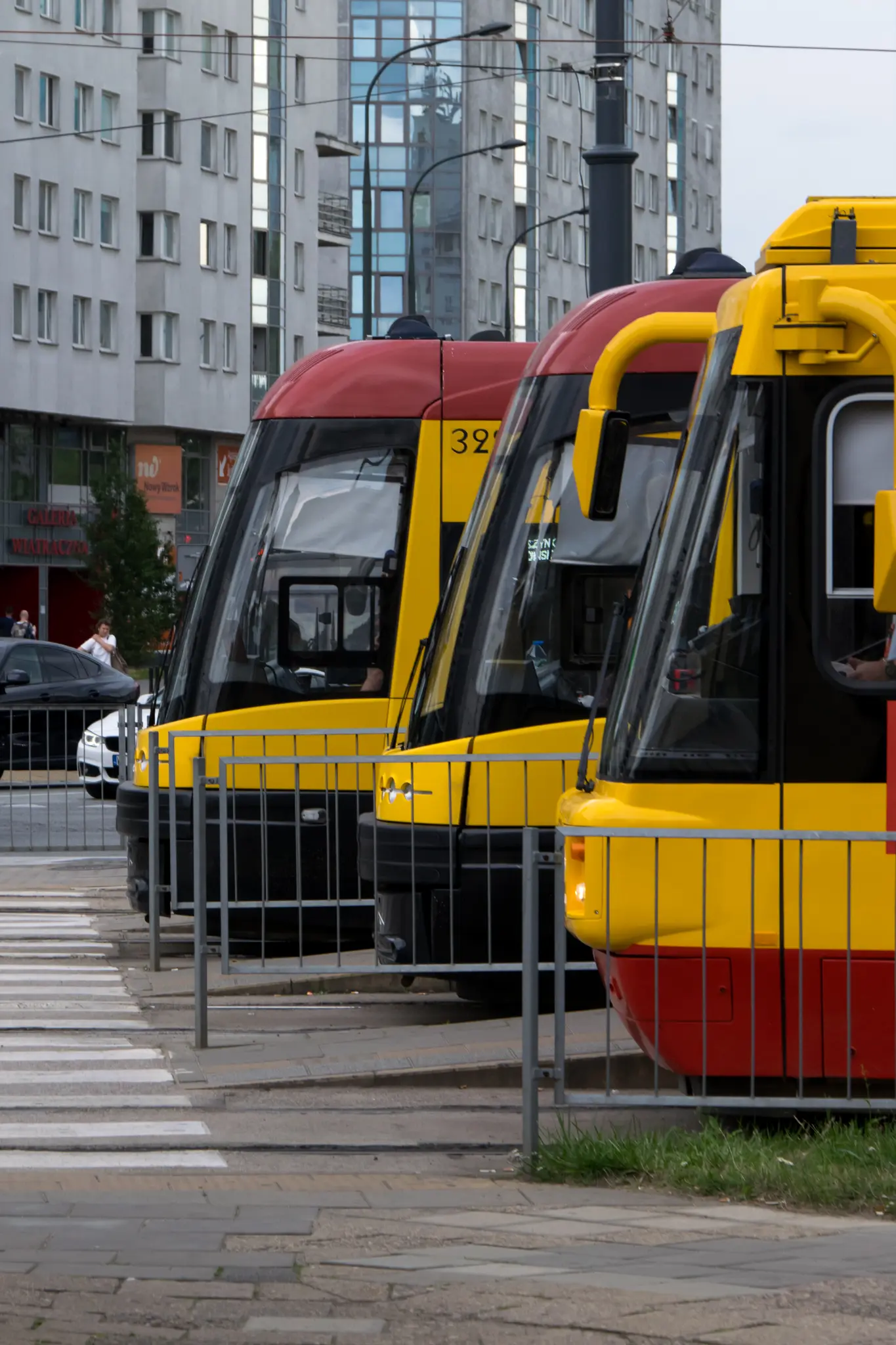 3 trams viewed from side, every further one is stopped closer to the crosswalk