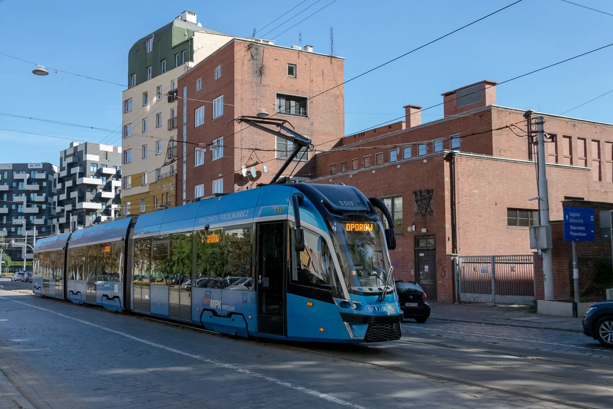 blue tram with post-modernist Polish™ architecture in background