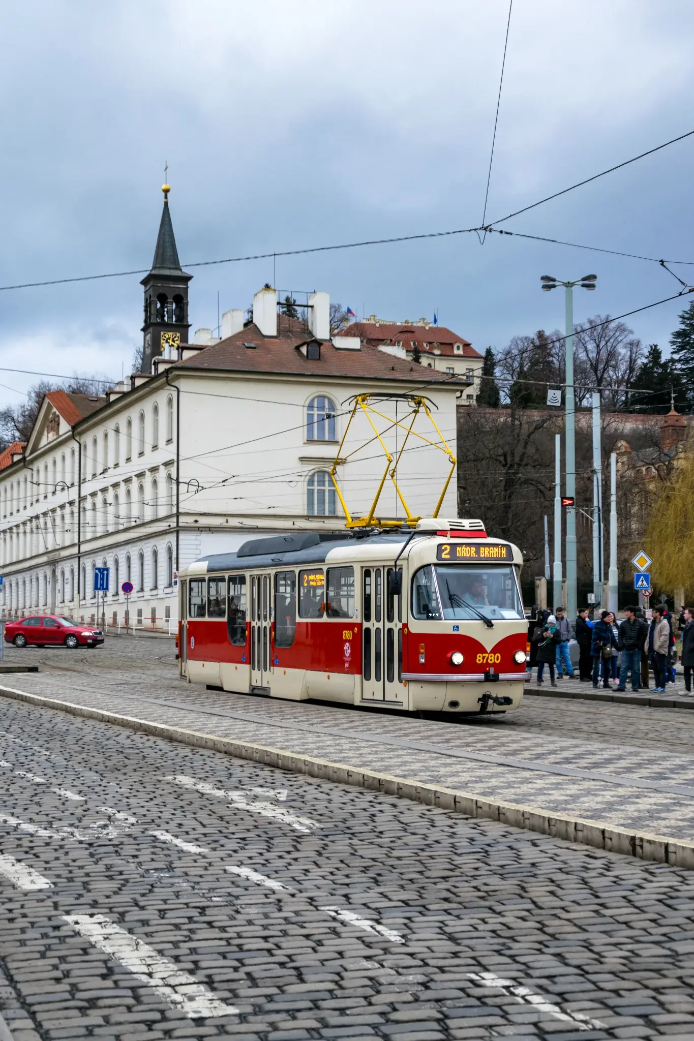 old white-red tram on a cobble street and a building in the background 