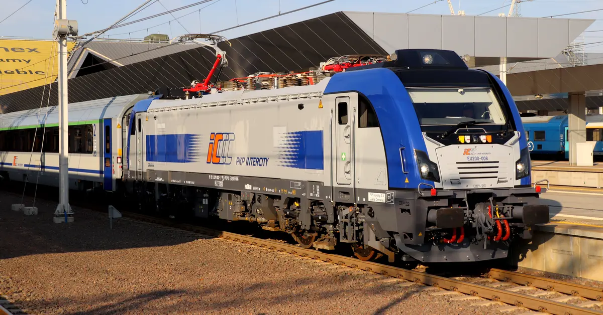 silver-blue locomotive with coaches, standing at platforms