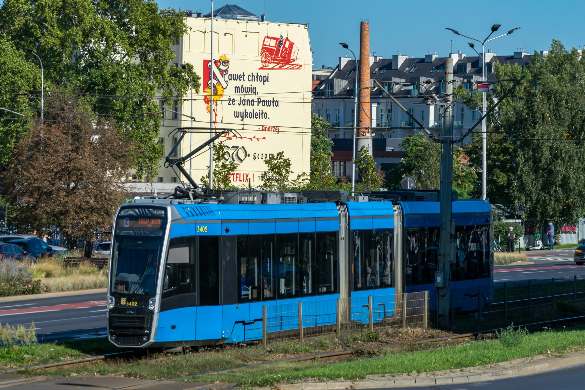blue tram with a "even peasants know that Jan Paweł derailed" ad for a kitsch Netflix series, context here: Wrocław is known for lots of tram derailments (however that has changed in last 3 years) and this photo was made on plac Jana Pawła II