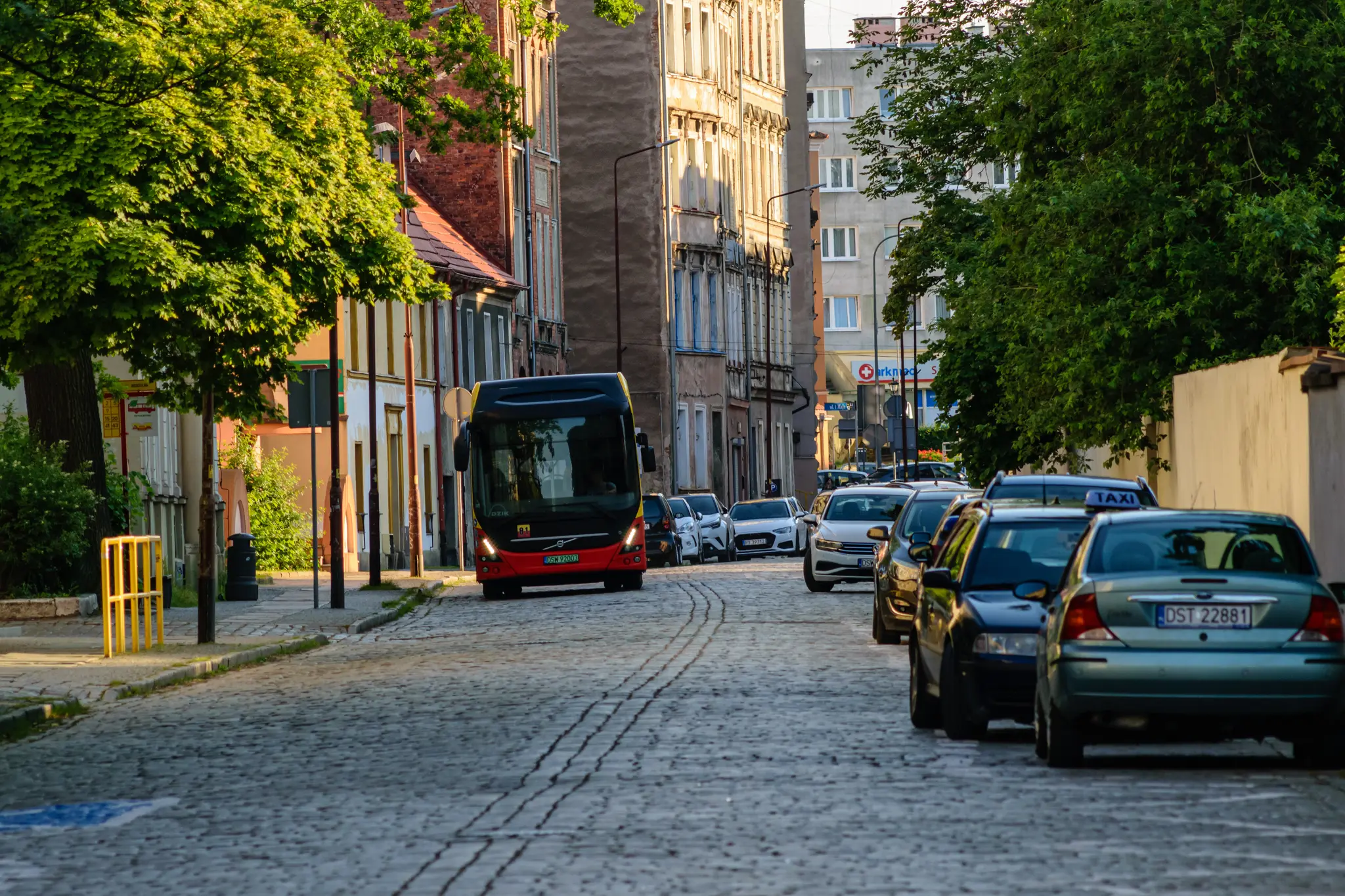 Yellow-red bus riding on cobblestone road