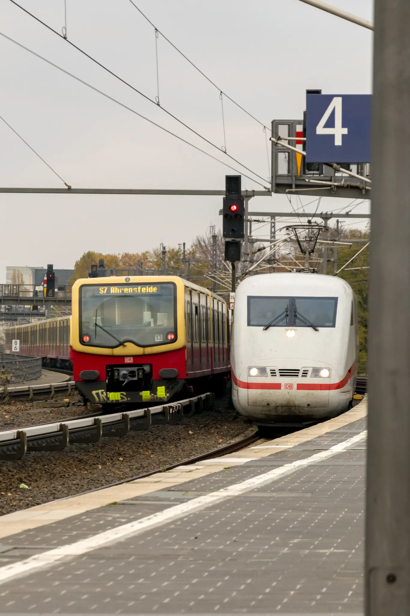 Yellow-red Berlin S-Bahn train of class 485 next to white ICE 1 train