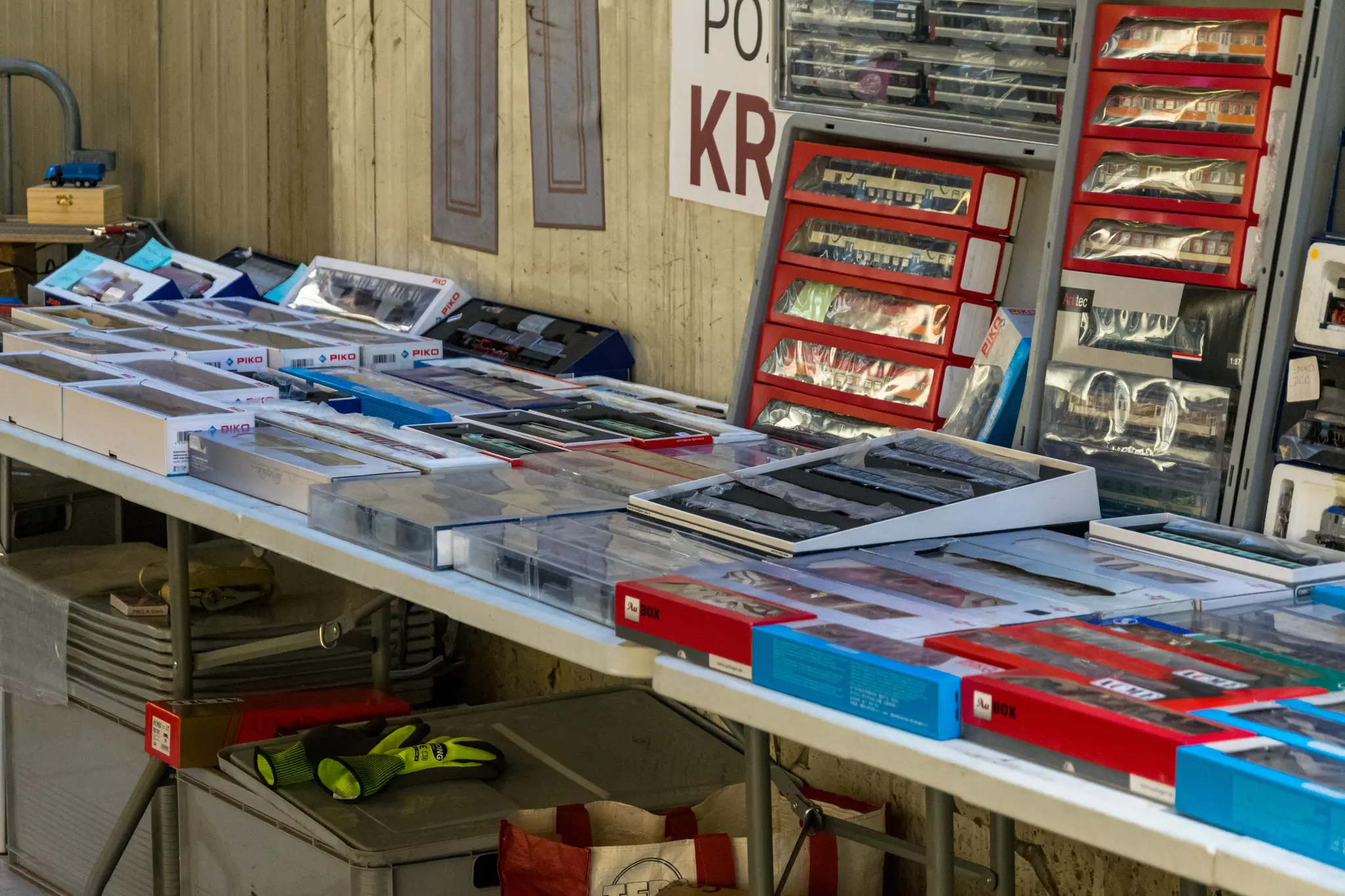 display of various model train accessories and parts arranged on tables with boxes and racks in a tram depot