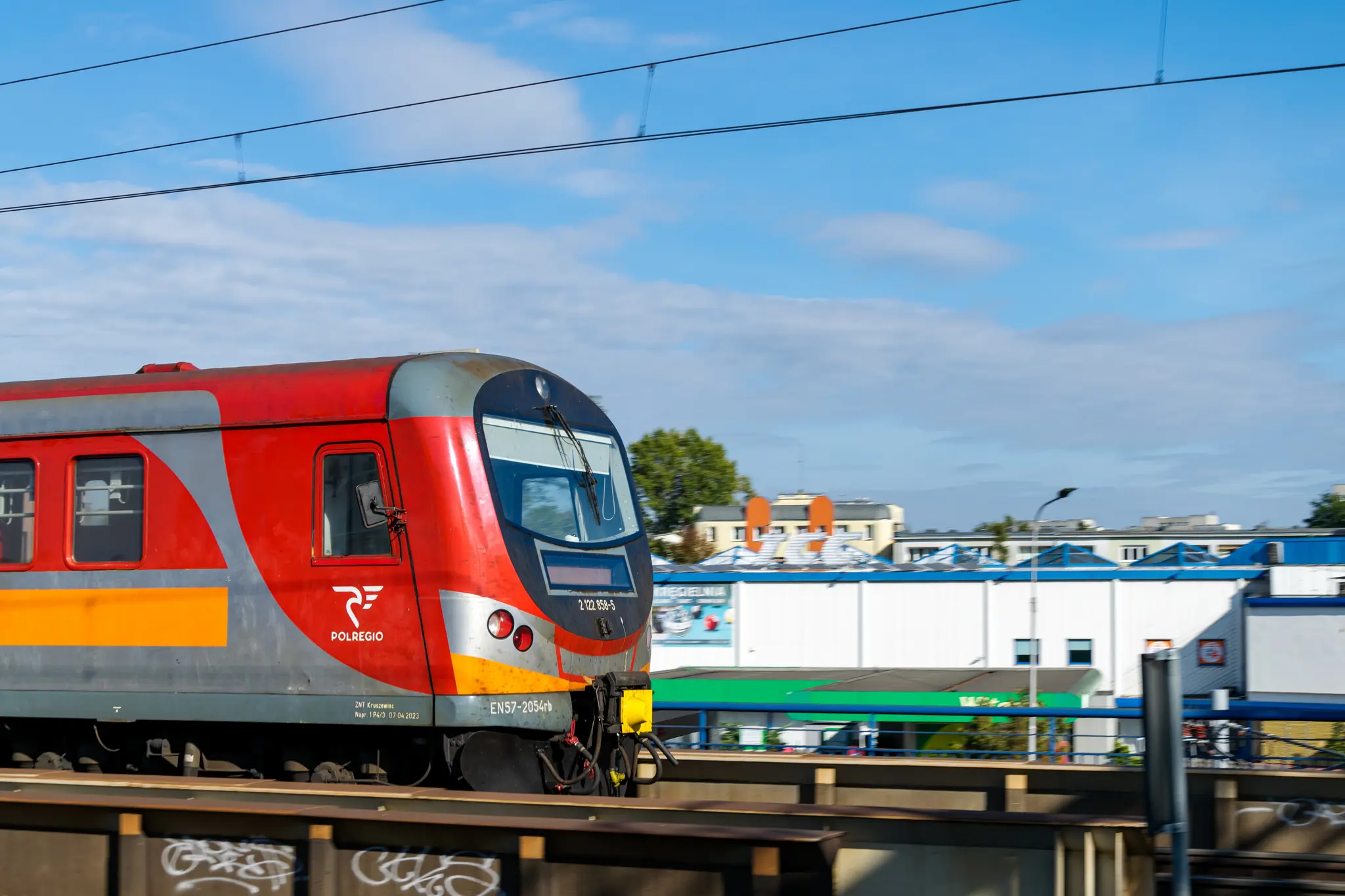 Red-orange EN57 SPOT leaving the station