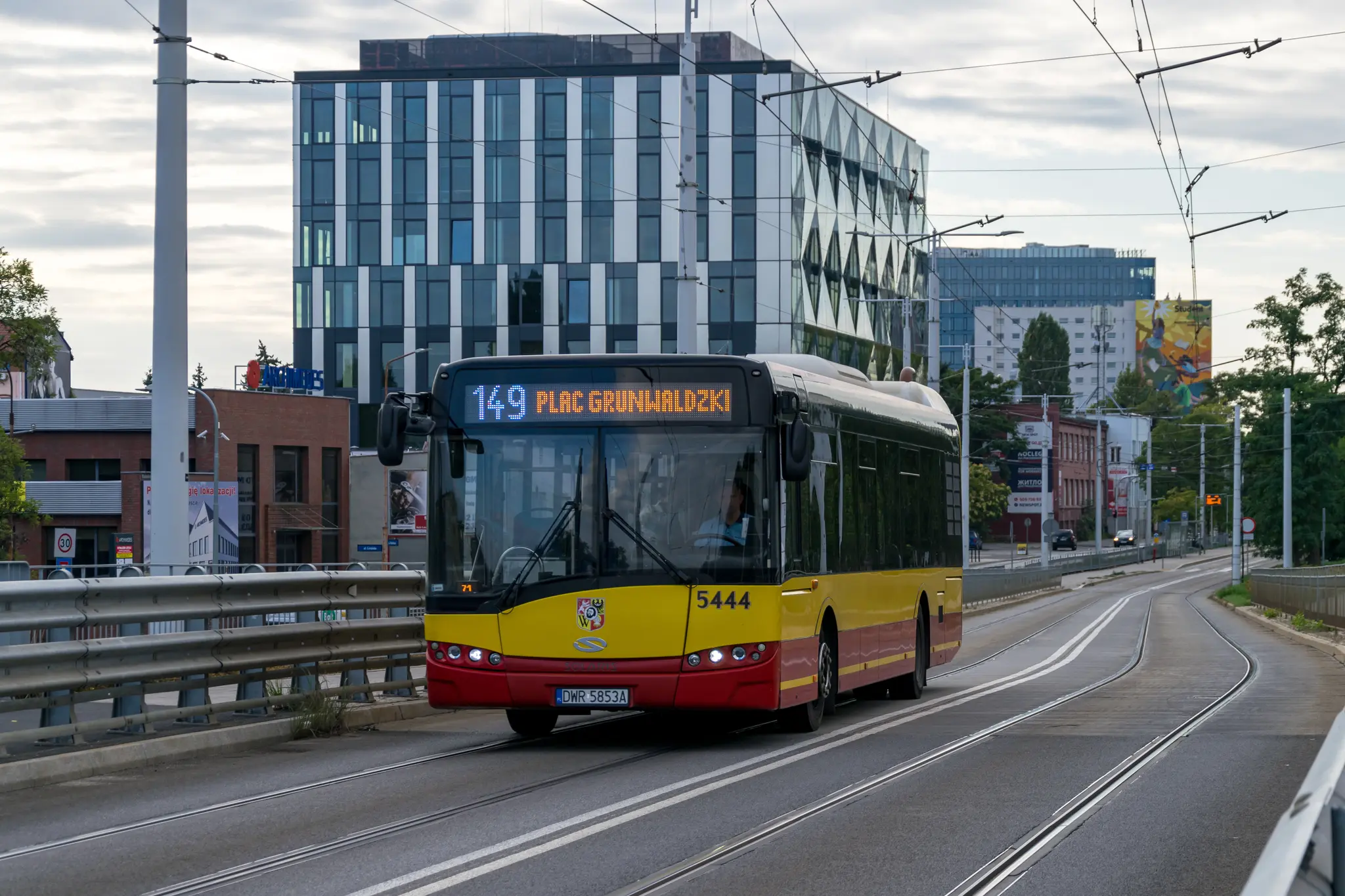 Yellow-red 3rd gen Solaris Urbino 12 bus at a bridge