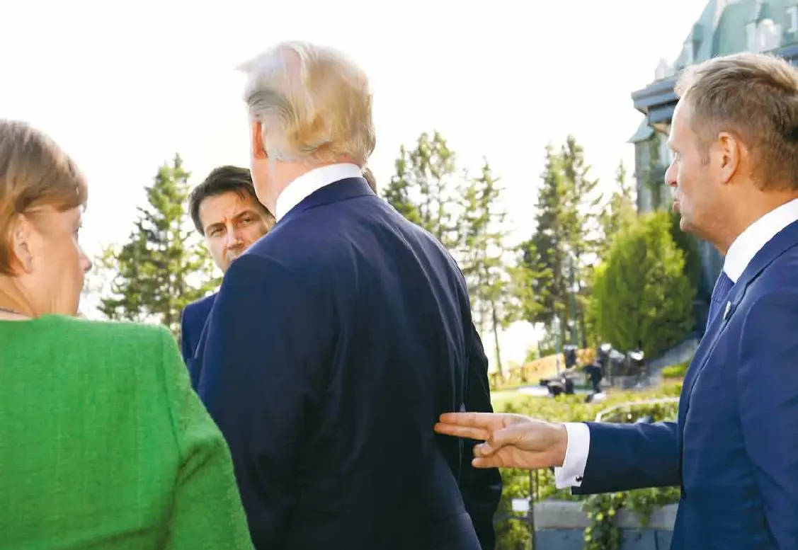 Donald Tusk pointing a finger gun into Trumps back