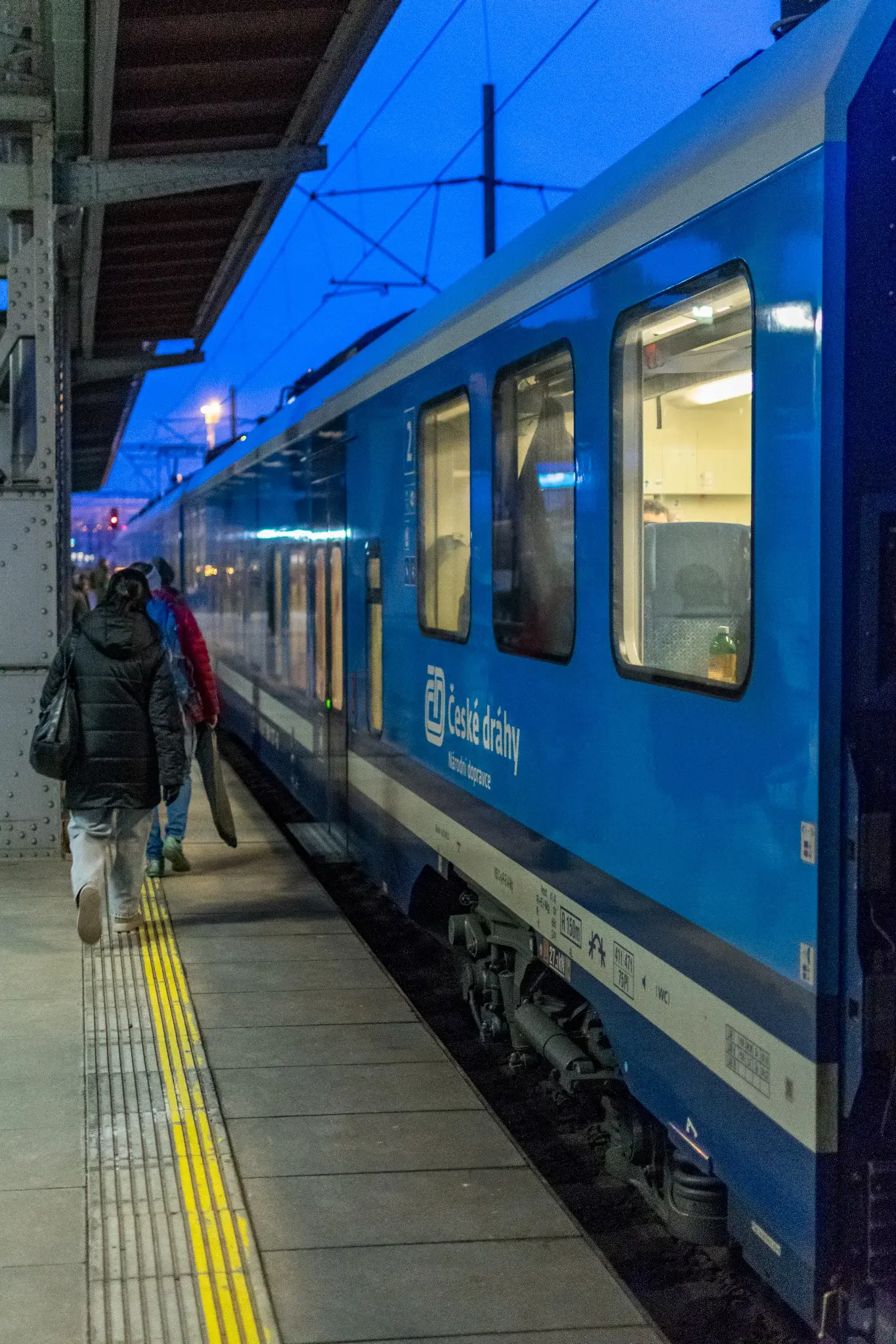 blue-white train stopped at a platform, there's a steel pillar quite close to platform edge